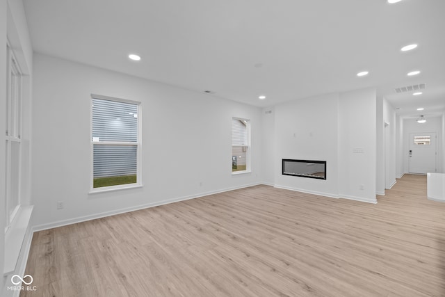 unfurnished living room featuring a healthy amount of sunlight and light hardwood / wood-style floors