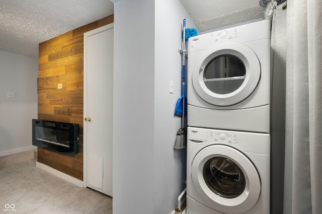 laundry room featuring light carpet, a textured ceiling, stacked washer / dryer, and wooden walls