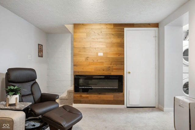 interior space featuring a fireplace, stacked washer and clothes dryer, a textured ceiling, and wood walls