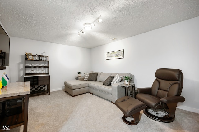 living room with a textured ceiling, light colored carpet, and rail lighting