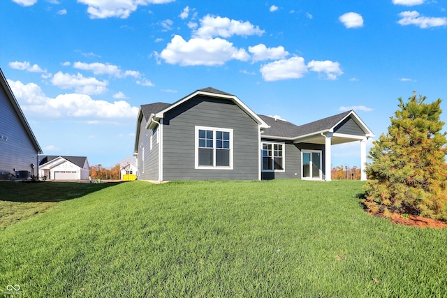 rear view of property with a garage and a lawn