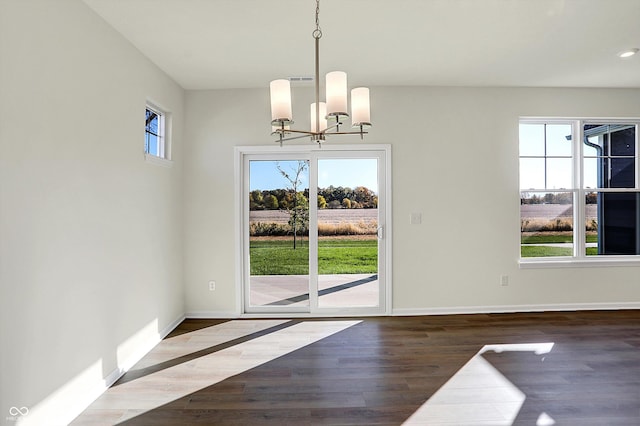 unfurnished dining area with baseboards, a chandelier, and wood finished floors