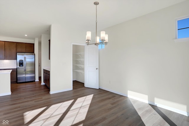 unfurnished dining area featuring an inviting chandelier and dark hardwood / wood-style flooring