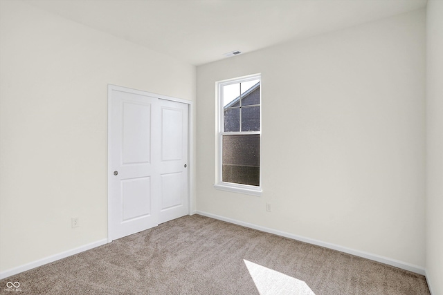 carpeted spare room with baseboards and visible vents