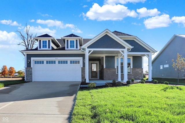 craftsman house featuring a porch, a front yard, concrete driveway, and stone siding