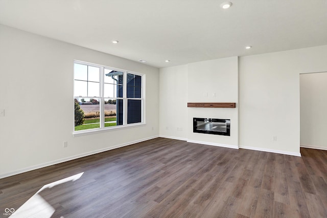 unfurnished living room with recessed lighting, baseboards, and dark wood finished floors