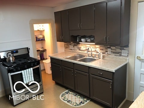 kitchen featuring decorative backsplash, sink, and stainless steel range with gas stovetop