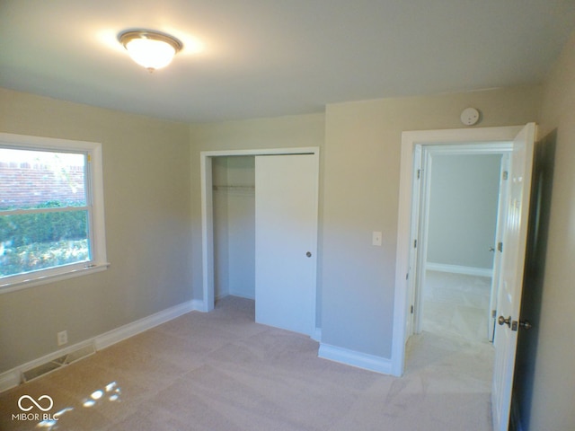 unfurnished bedroom with light carpet and a closet