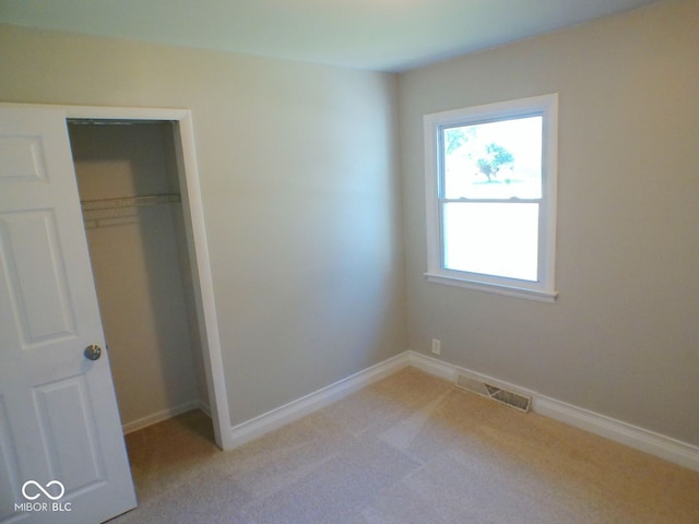 unfurnished bedroom featuring a closet and light colored carpet