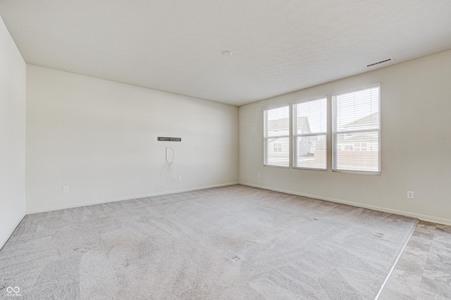 carpeted empty room featuring a textured ceiling