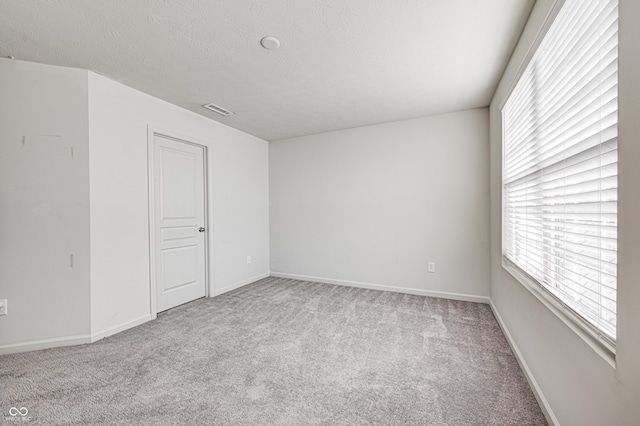 carpeted spare room featuring a textured ceiling