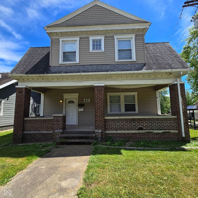 709 W Riverside Ave, Muncie, IN 47303 - view of front of home with a porch, brick siding, a front yard, and roof with shingles