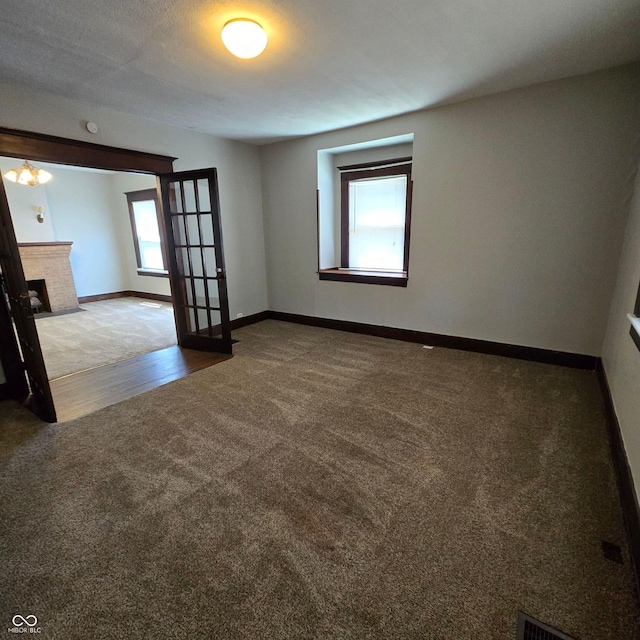 unfurnished room with hardwood / wood-style flooring, a textured ceiling, and a brick fireplace