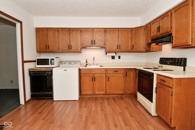 kitchen featuring washer / dryer, a textured ceiling, light wood-type flooring, sink, and white appliances