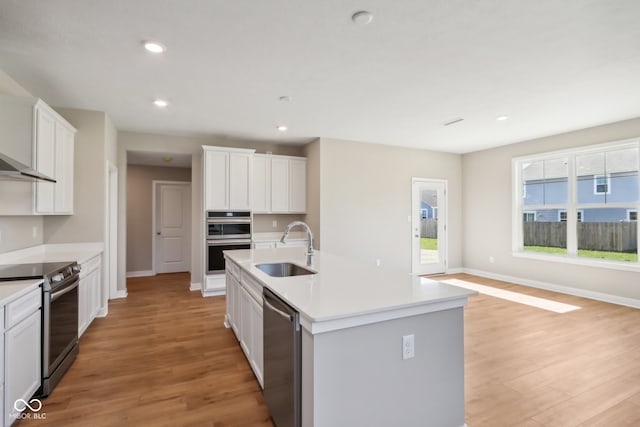 kitchen featuring a kitchen island with sink, sink, stainless steel appliances, and light hardwood / wood-style flooring