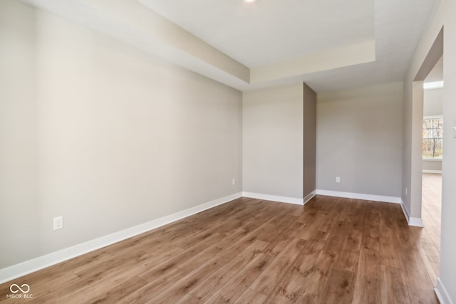 unfurnished room with a raised ceiling and hardwood / wood-style floors