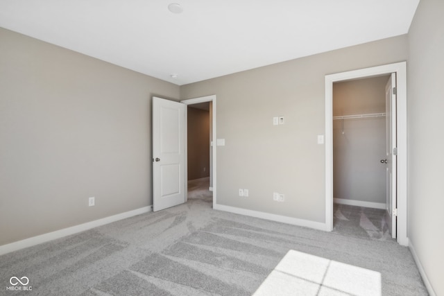 unfurnished bedroom featuring a spacious closet, light carpet, and a closet