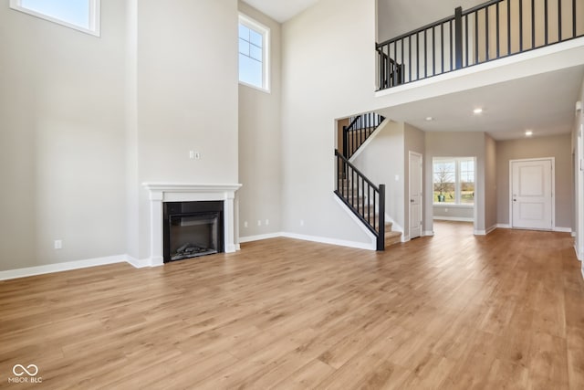 unfurnished living room with a high ceiling and light hardwood / wood-style floors