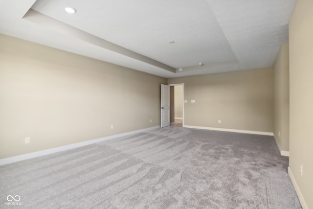 unfurnished room featuring a tray ceiling and carpet