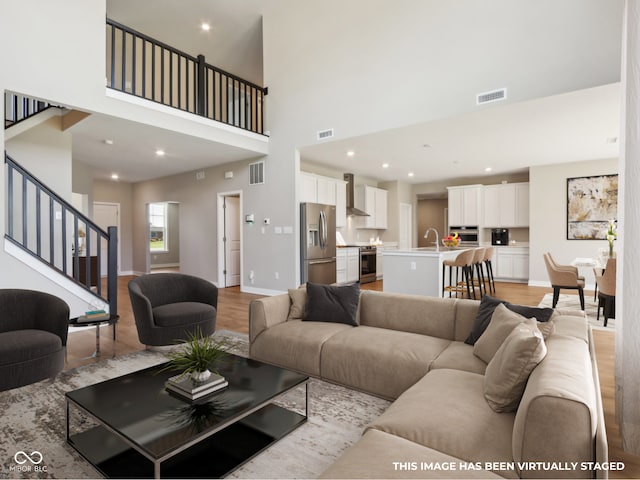 living room with a high ceiling, light wood-type flooring, and sink