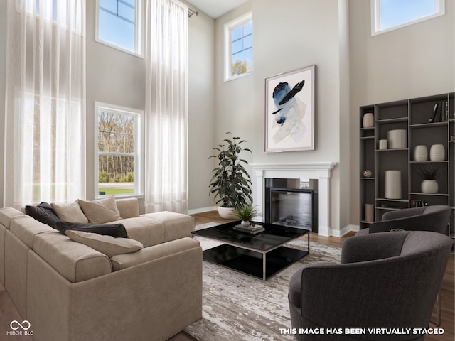 living room with hardwood / wood-style flooring, a towering ceiling, and a wealth of natural light