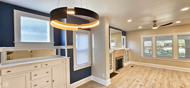 kitchen featuring a stone fireplace, ceiling fan, decorative light fixtures, and a wealth of natural light