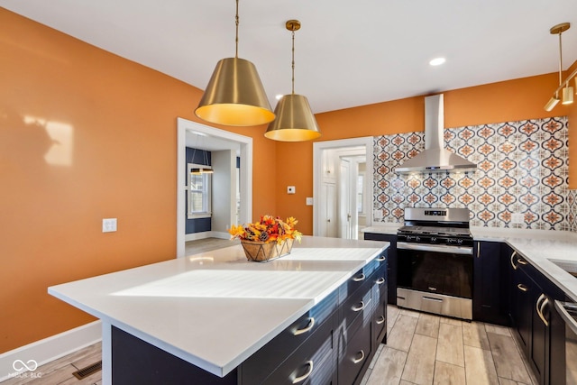 kitchen featuring pendant lighting, wall chimney exhaust hood, a center island, and stainless steel appliances