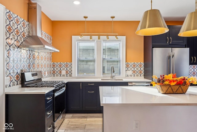 kitchen featuring sink, wall chimney exhaust hood, decorative light fixtures, decorative backsplash, and appliances with stainless steel finishes