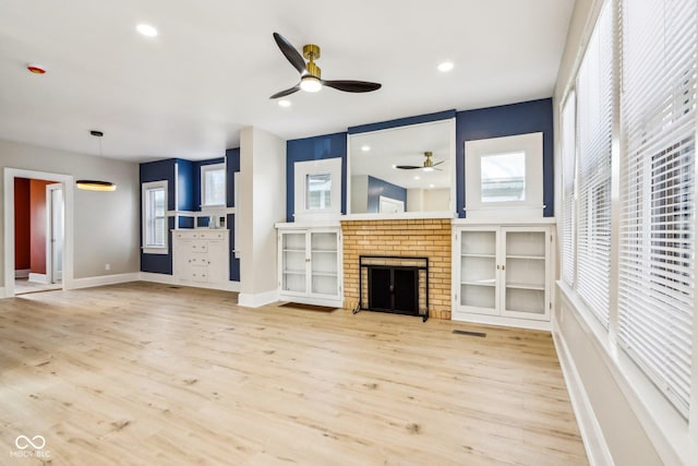 unfurnished living room with a fireplace, light hardwood / wood-style flooring, and a healthy amount of sunlight