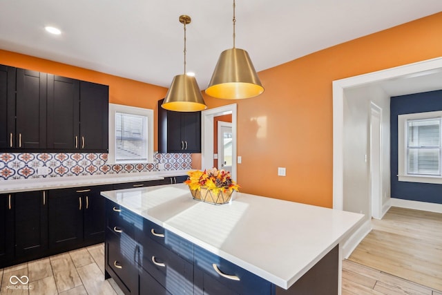 kitchen featuring a kitchen island, light wood-type flooring, backsplash, and hanging light fixtures