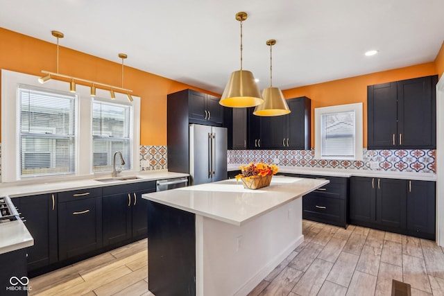 kitchen with a center island, backsplash, sink, hanging light fixtures, and stainless steel appliances