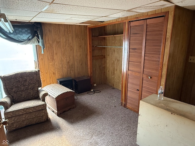 unfurnished room featuring wooden walls, a paneled ceiling, and carpet