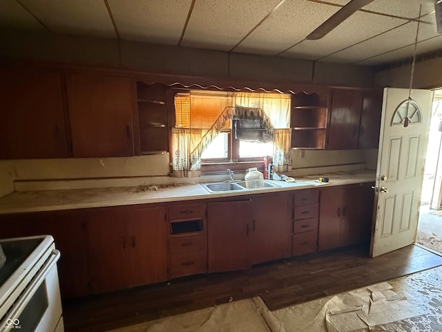 kitchen featuring dark wood-type flooring, sink, stove, and a drop ceiling