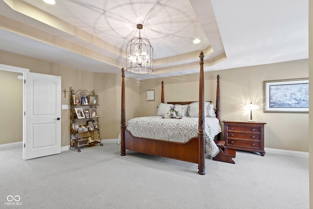 bedroom featuring carpet, a tray ceiling, and an inviting chandelier