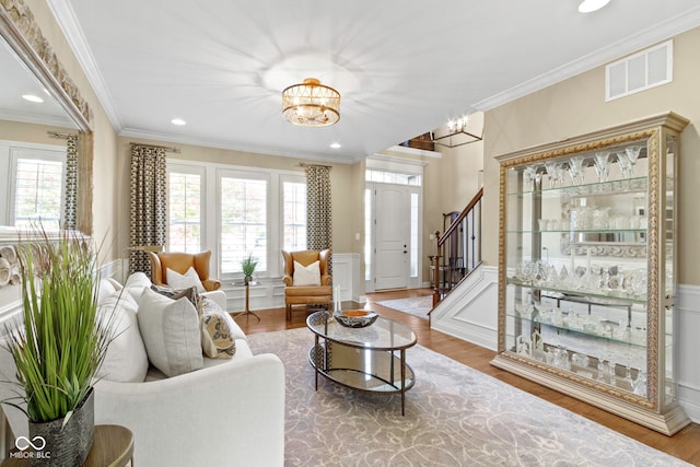 living room with wood-type flooring, crown molding, and an inviting chandelier