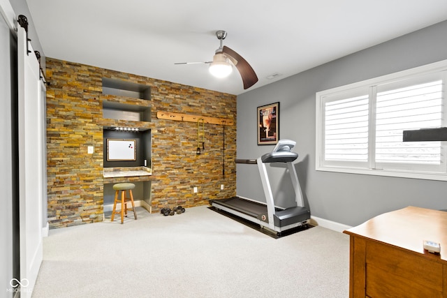 workout room featuring a barn door, ceiling fan, and carpet floors