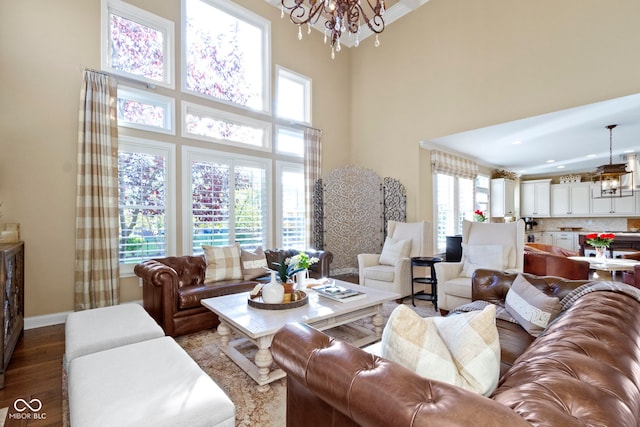 living room featuring a notable chandelier, a healthy amount of sunlight, a towering ceiling, and dark hardwood / wood-style floors