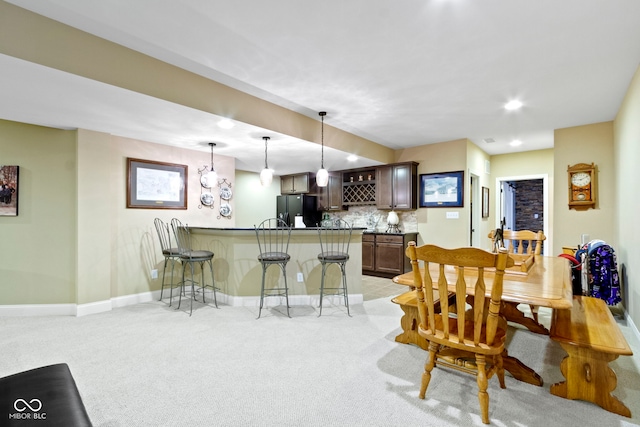 dining space with bar area and light colored carpet