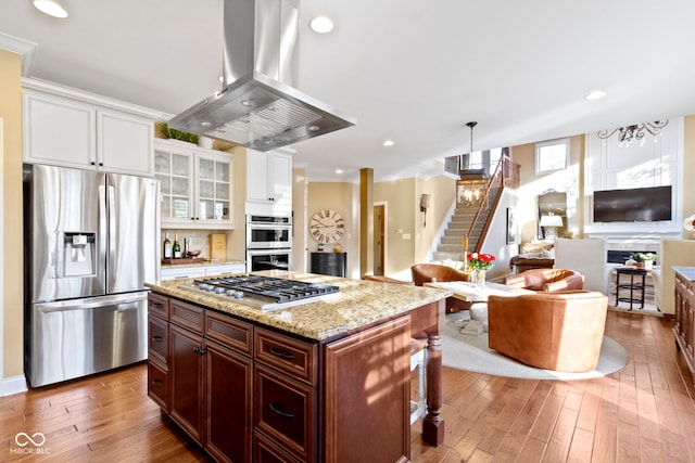 kitchen featuring island range hood, pendant lighting, hardwood / wood-style flooring, and appliances with stainless steel finishes