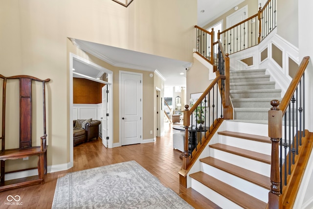 staircase with crown molding, plenty of natural light, a high ceiling, and hardwood / wood-style flooring