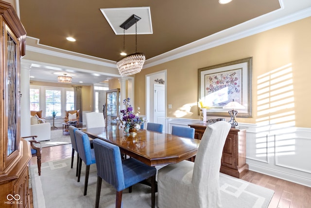 dining space with light hardwood / wood-style floors, ornate columns, crown molding, and a chandelier