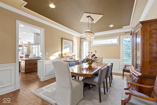 dining room with ornamental molding, light hardwood / wood-style flooring, and a notable chandelier