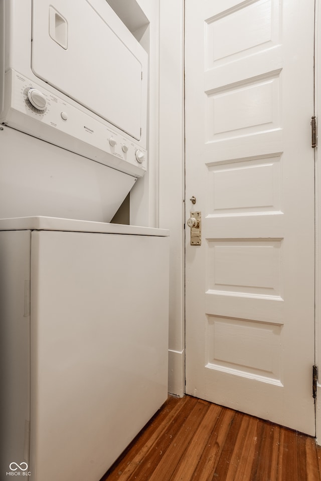 washroom with stacked washing maching and dryer and dark hardwood / wood-style floors