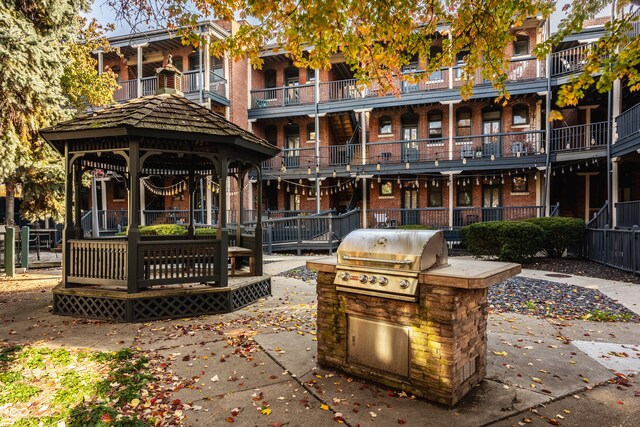 view of patio / terrace with a balcony, a gazebo, exterior kitchen, and area for grilling