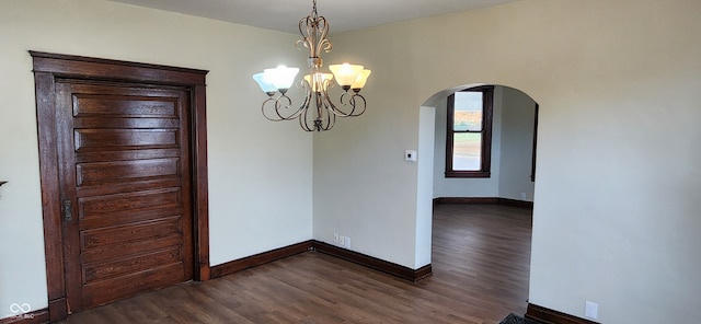 unfurnished dining area with dark wood-type flooring and a chandelier