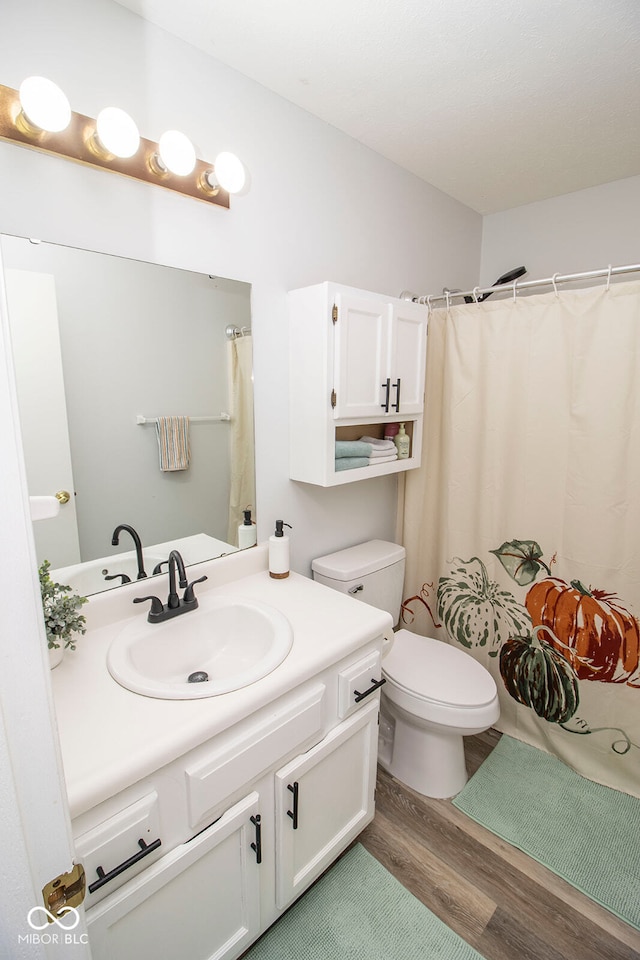 bathroom with toilet, vanity, and hardwood / wood-style flooring