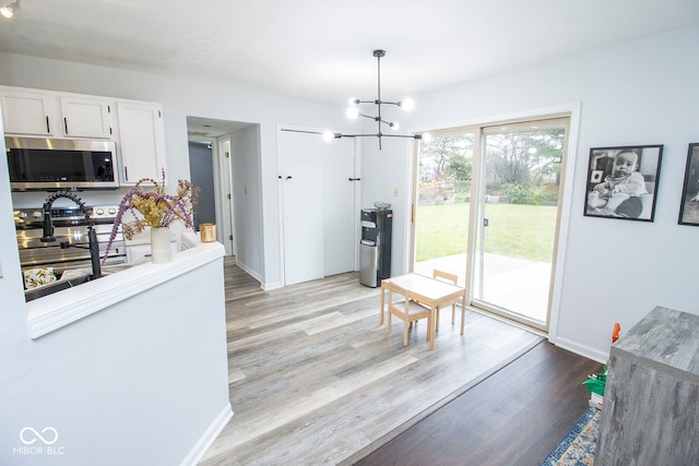 kitchen with pendant lighting, an inviting chandelier, light hardwood / wood-style floors, and white cabinets