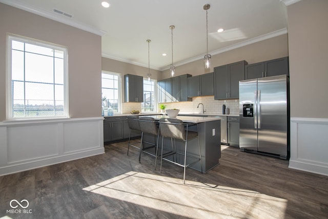 kitchen with pendant lighting, a kitchen island, stainless steel refrigerator with ice dispenser, gray cabinets, and a breakfast bar area