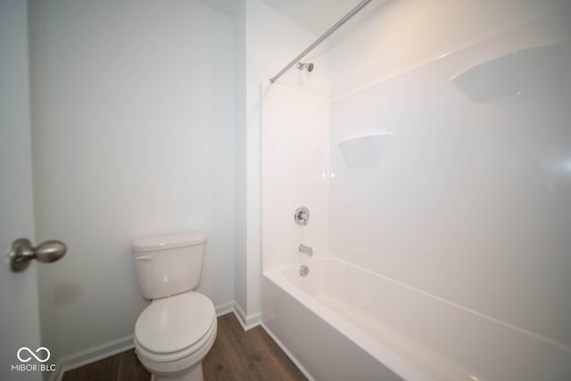 bathroom with hardwood / wood-style flooring, bathtub / shower combination, and toilet