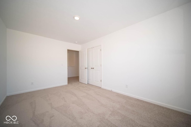 unfurnished bedroom featuring light carpet and a closet